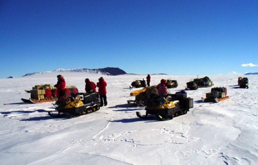 A collection of sno-mos with sledges stopping during the traverse to tie on boxes that had fallen off.